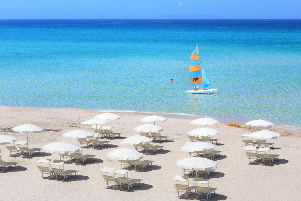 weisse Sonnenschirme auf hellem Sand und türkisfarbenes Wasser dies ist der Strand des Hotels Le Dune, Badesi - meer sardinien urlaub