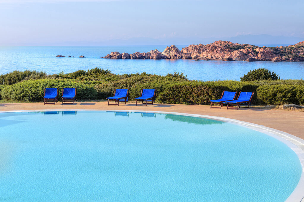 Der Pool mit Blick auf das Meer und die roten Felsen von Isola Rossa Hotel Relax Thalasso & Spa Torreruja, Isola Rossa - meer sardinien urlaub