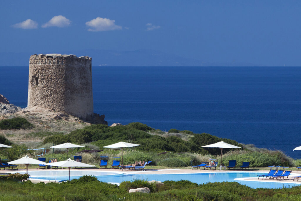 Stimmungsvoller Blick auf inseltypischen Sarazenenturm und Pool des Hotels Torreruja, Isola Rossa mit Meereshintergrund - meer sardinien urlaub
