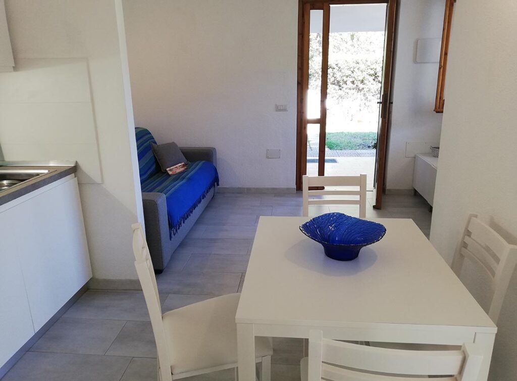 Blick vom Kuechenbereich in den Wohnbereich und der Eingangstuer des Ferienhauses Elea, Geremeas - meer sardinien urlaub