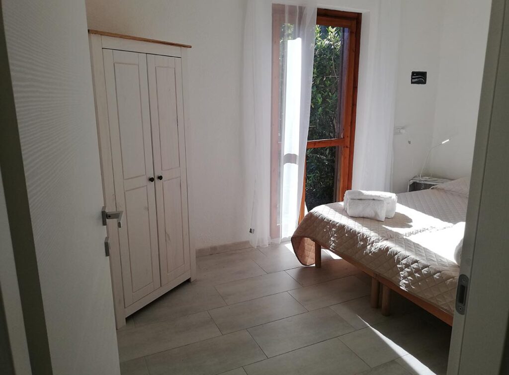 Blick in das erste Schlafzimmer mit einem Doppel- oder zwei Einzelbetten und Safe, Ferienhaus Elea, Geremeas - meer sardinien urlaub