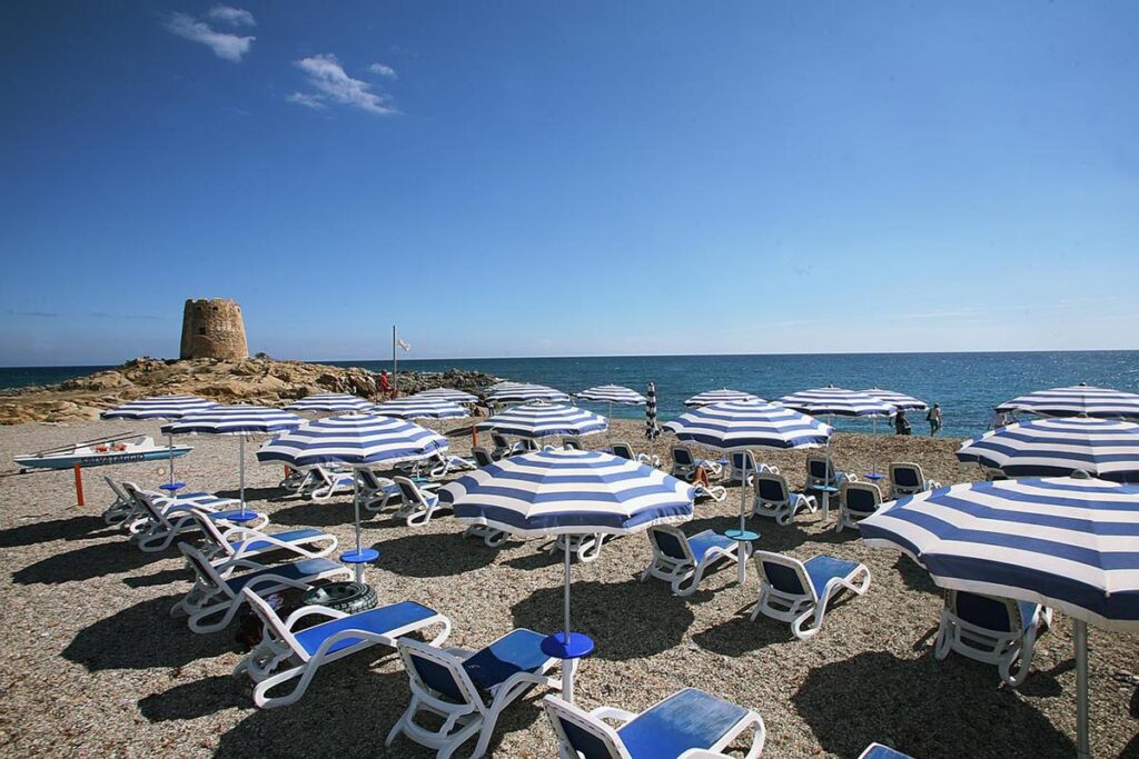 die Sonnenschirme und -liegen mit Sarazenenturm im Hintergrund am Hotel La Torre, Barisardo - meer sardinien urlaub