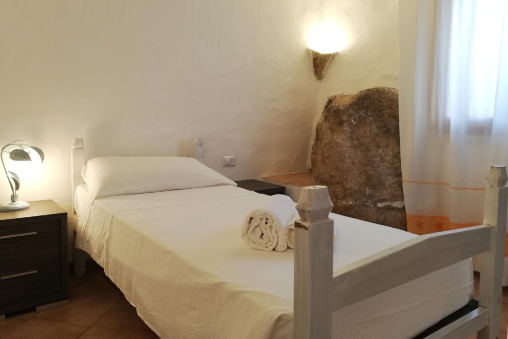 Ein Schlafzimmer des Ferienhauses Barbara mit Felsen als besonderer Blickfang - meer sardinien urlaub
