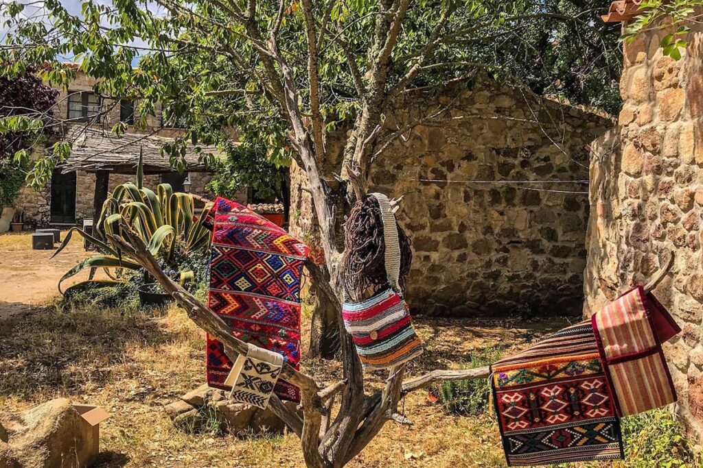 Gewebte Teppiche und Satteltaschen zieren einen Baum im Agriturismo Il Muto di Gallura bei Aggius - meer sardinien urlaub