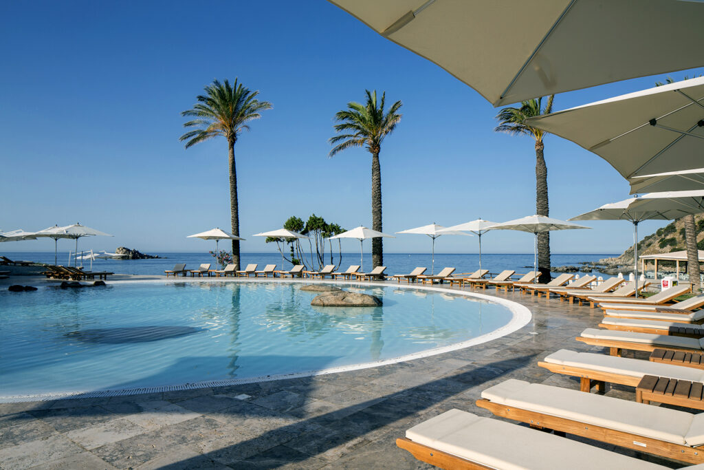 Blick auf den Pool mit Sonnnenliegen und Meerblick des Hotel Falkensteiner Capo Boi bei Villasimius - meer sardinien urlaub