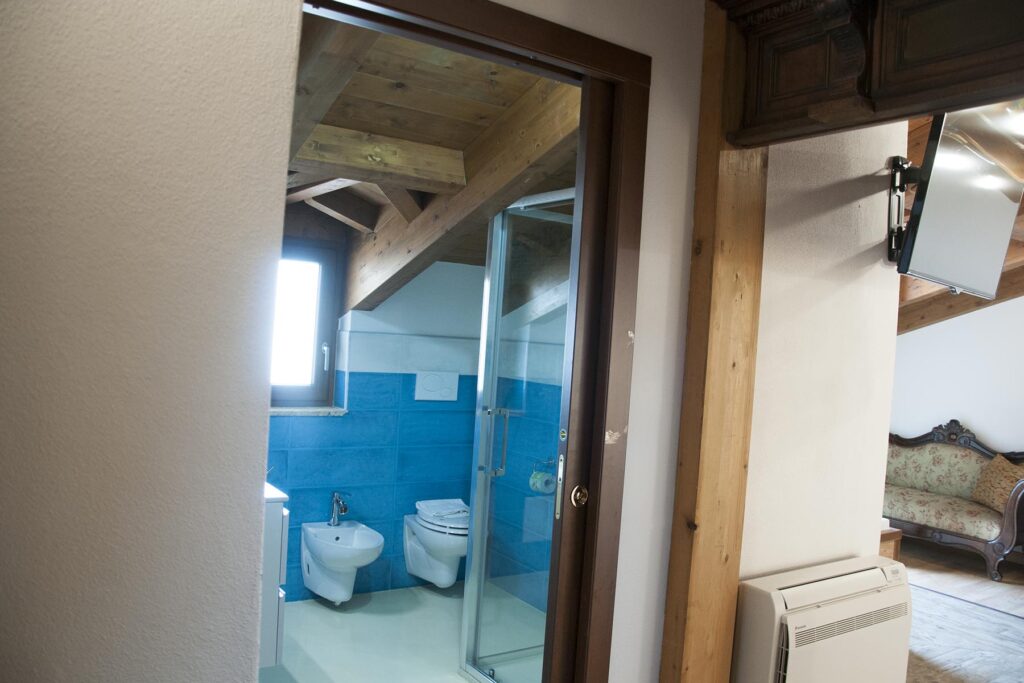 Das Badezimmer der Juniosuite Prestige 304 mit schweren Holzbalken an der Decke, Hotel Maison de Charme Bienestar, Alghero - meer sardinien urlaub