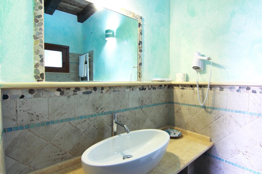 ein Waschbecken mit schönem Wandspiegel im Agriturismo Su Passu, Alghero - meer sardinien urlaub