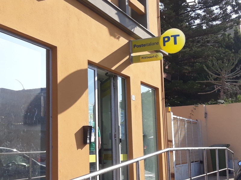 Das gelbe Schild mit "PT" - Poste Italiane - weist auf die Post hin, Sardinien. - meer sardinien urlaub