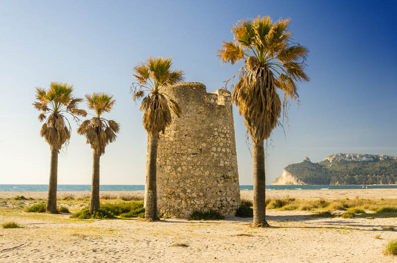 Sarazenenturm mit Königspalmen am Strand Poetto der Inselhauptstadt Cagliari mit Felsklippe Sella del Diavolo im Hintergrund, Sardinien - meer sardinien urlaub