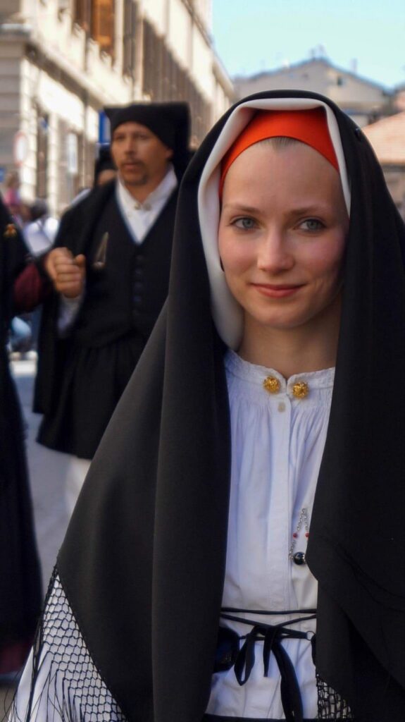 eine schöne Nahaufnahme einer Frau in einem sardischen Trachtenkleid während des Folkloreumzugs Cavalcata di Sassari - meer sardinien urlaub